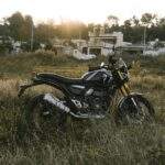 A black motorcycle parked in a field at sunset in Bengaluru, India, capturing outdoor adventure spirit.